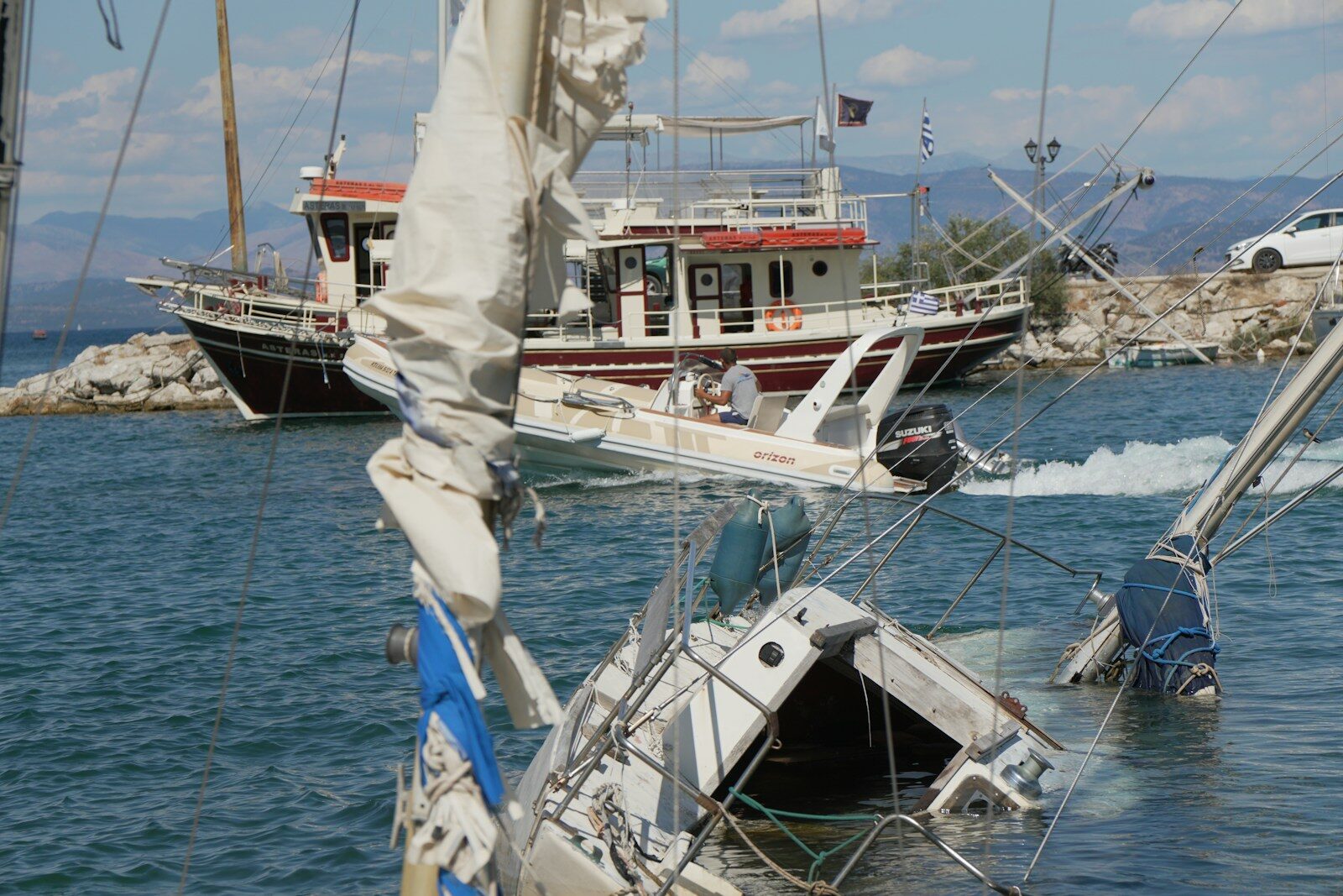 Partially sunken sailboat with other boats on a sunny day